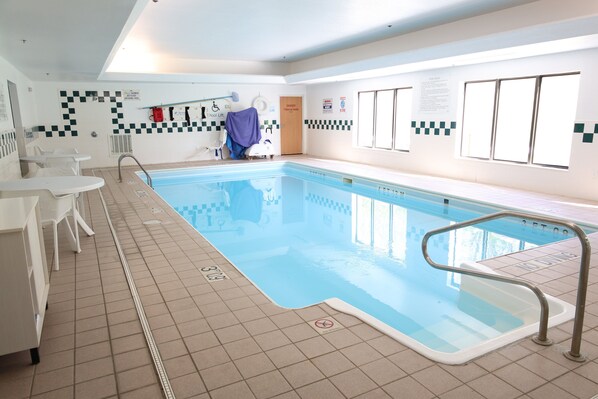 A swimming pool with a tiled deck, a lifeguard chair, and a pool lift.