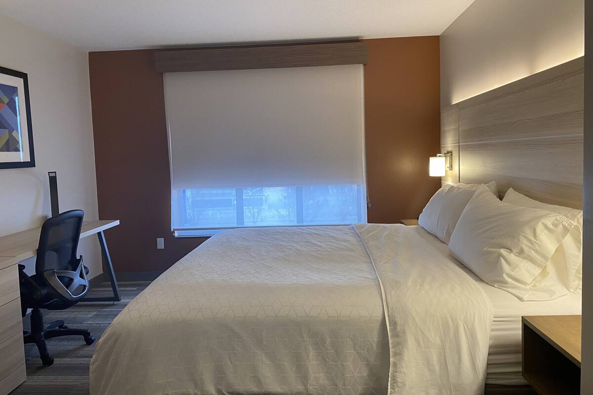 A hotel room with a bed, a desk, and a chair.
