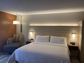 A hotel room with a large bed, bedside lamps, a nightstand with a phone, and a chair. - Holiday Inn Express Hotel & Suites Logansport by IHG (Logansport)