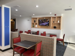 A restaurant with booths and tables, a television mounted on the wall, and a patterned wall design. - Holiday Inn Express Hotel & Suites Logansport by IHG (Logansport)