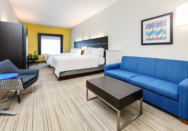 A hotel room with a bed, a blue sofa, a coffee table, and a desk with a chair. - Holiday Inn Express Hotel & Suites Cleburne by IHG (Cleburne)