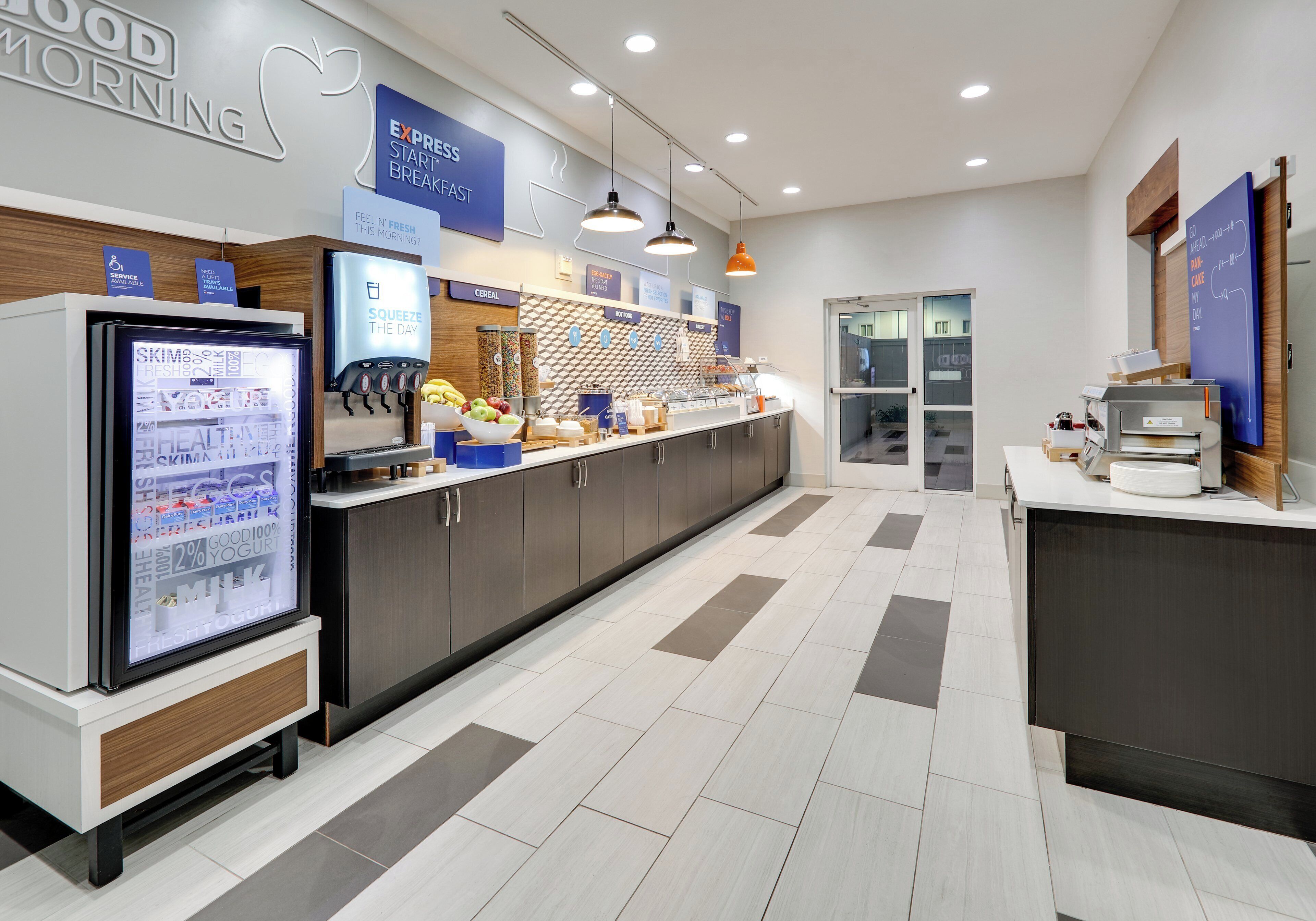 Un moderno espacio para desayunar con refrigerador, cafetera y diversas opciones de alimentos.