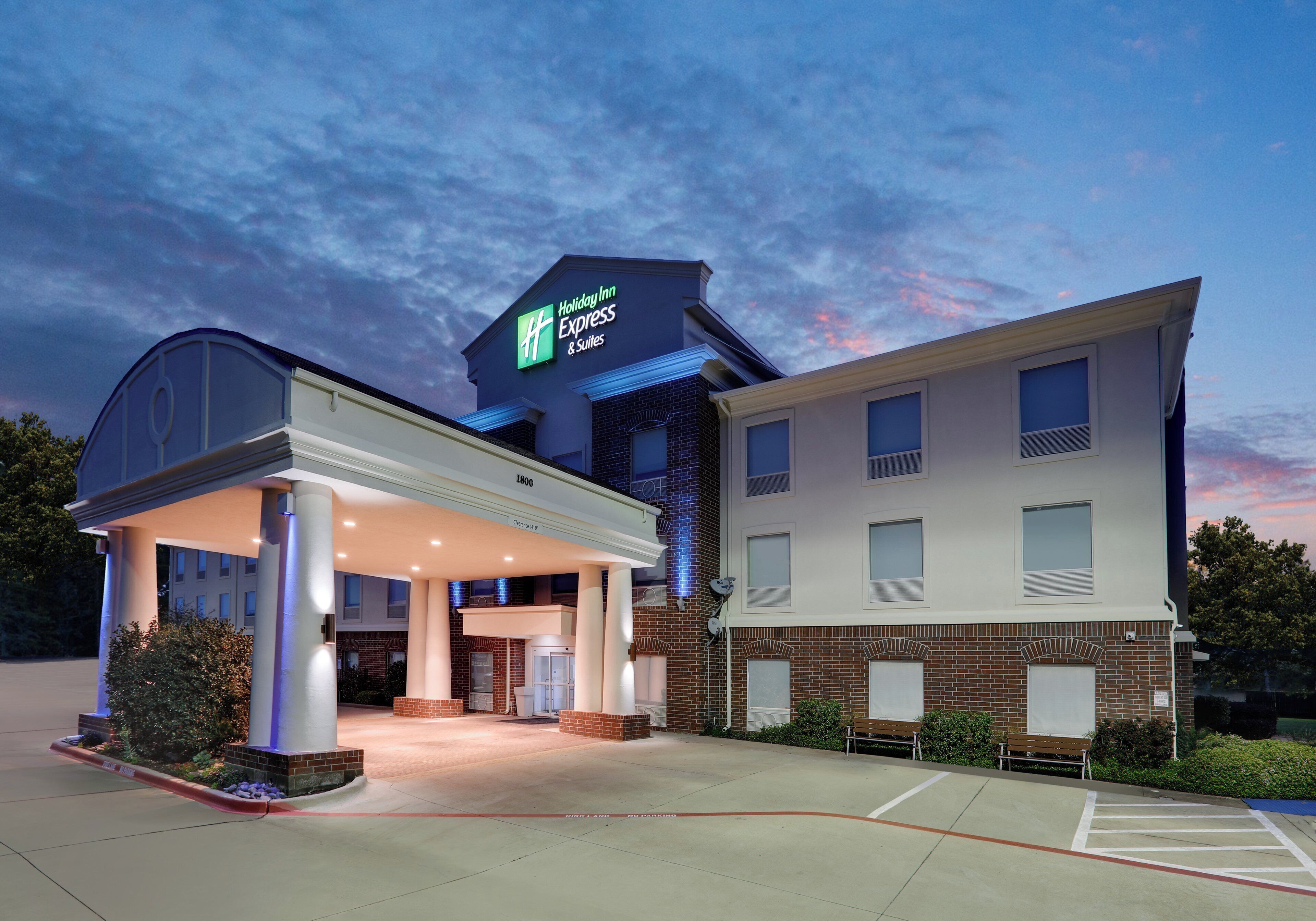 A Holiday Inn Express & Suites building with a covered entrance and a clear sky.
