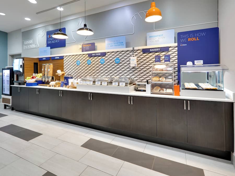 Un comptoir où l’on peut prendre le petit-déjeuner et qui propose diverses options de restauration, un rayon de produits de boulangerie et une machine à café.