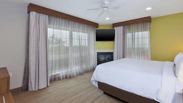 Camera d'albergo con un letto, tende, ventilatore a soffitto, televisore a schermo piatto e camino.
