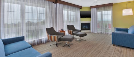 Habitación de hotel con un ventanal grande, dos sillones, un sofá, una mesita y un televisor de pantalla plana.