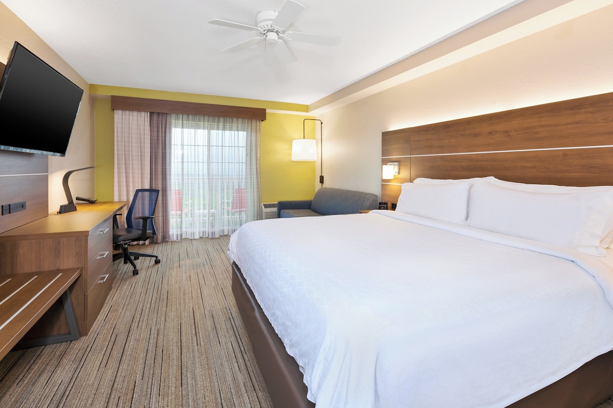 Une chambre d’hôtel équipée d’un lit, d’un bureau, d’une chaise, d’une télévision et d’un ventilateur de plafond.