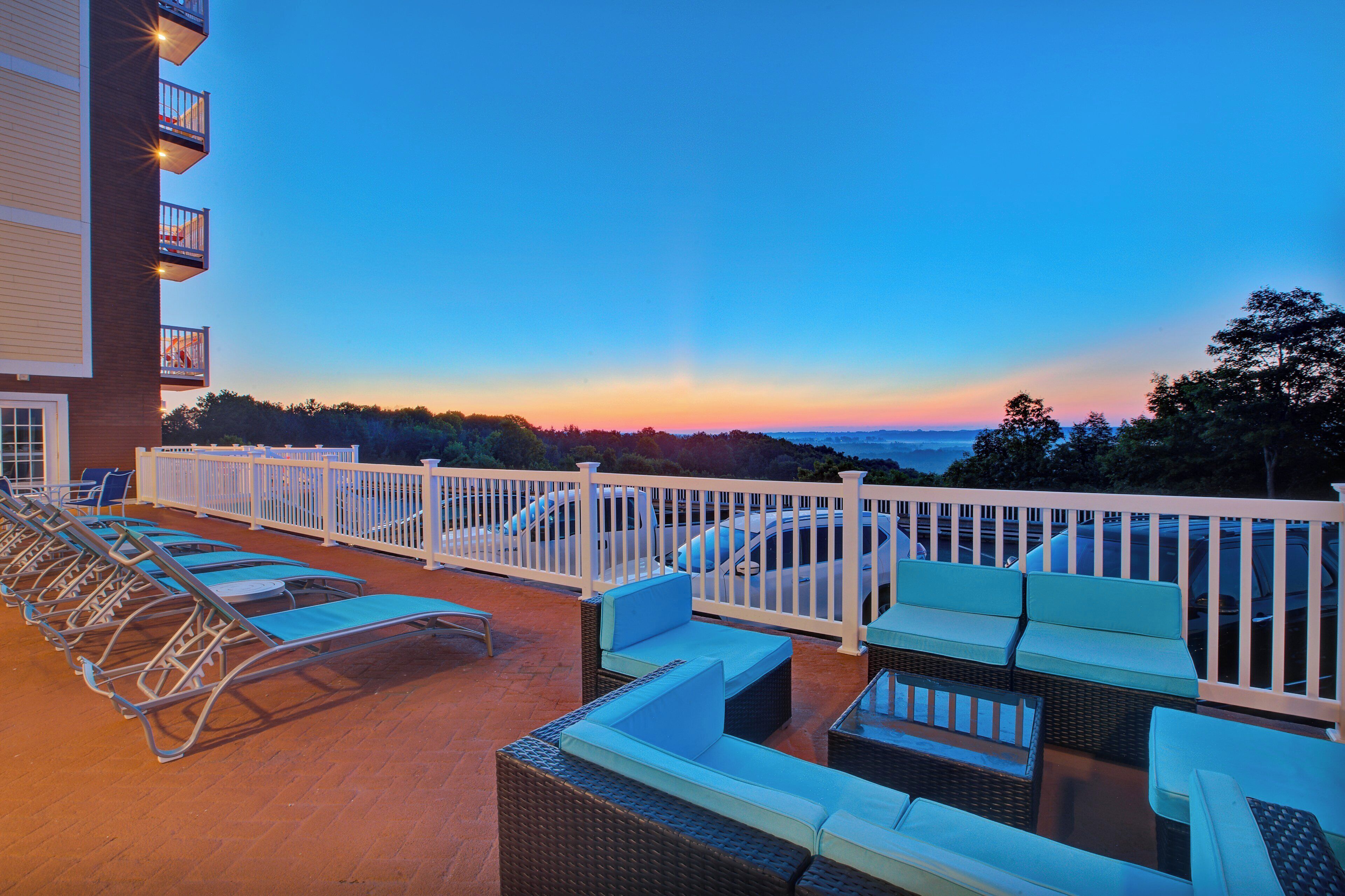 Une terrasse sur le toit, dotée de chaises longues et d’une balustrade blanche, offrant une vue panoramique.