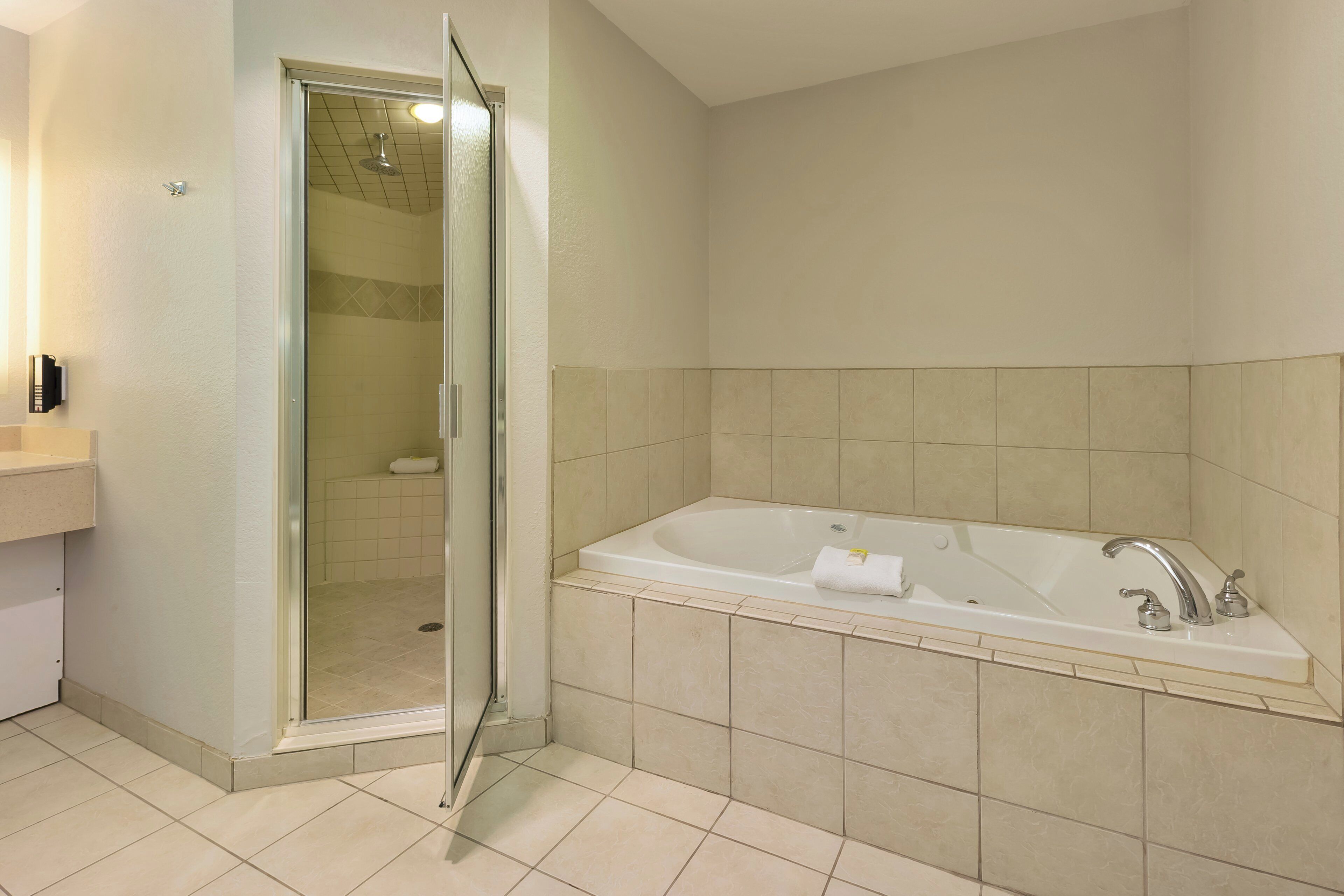 A bathroom with a glass shower enclosure, a bathtub, and a vanity with a mirror.