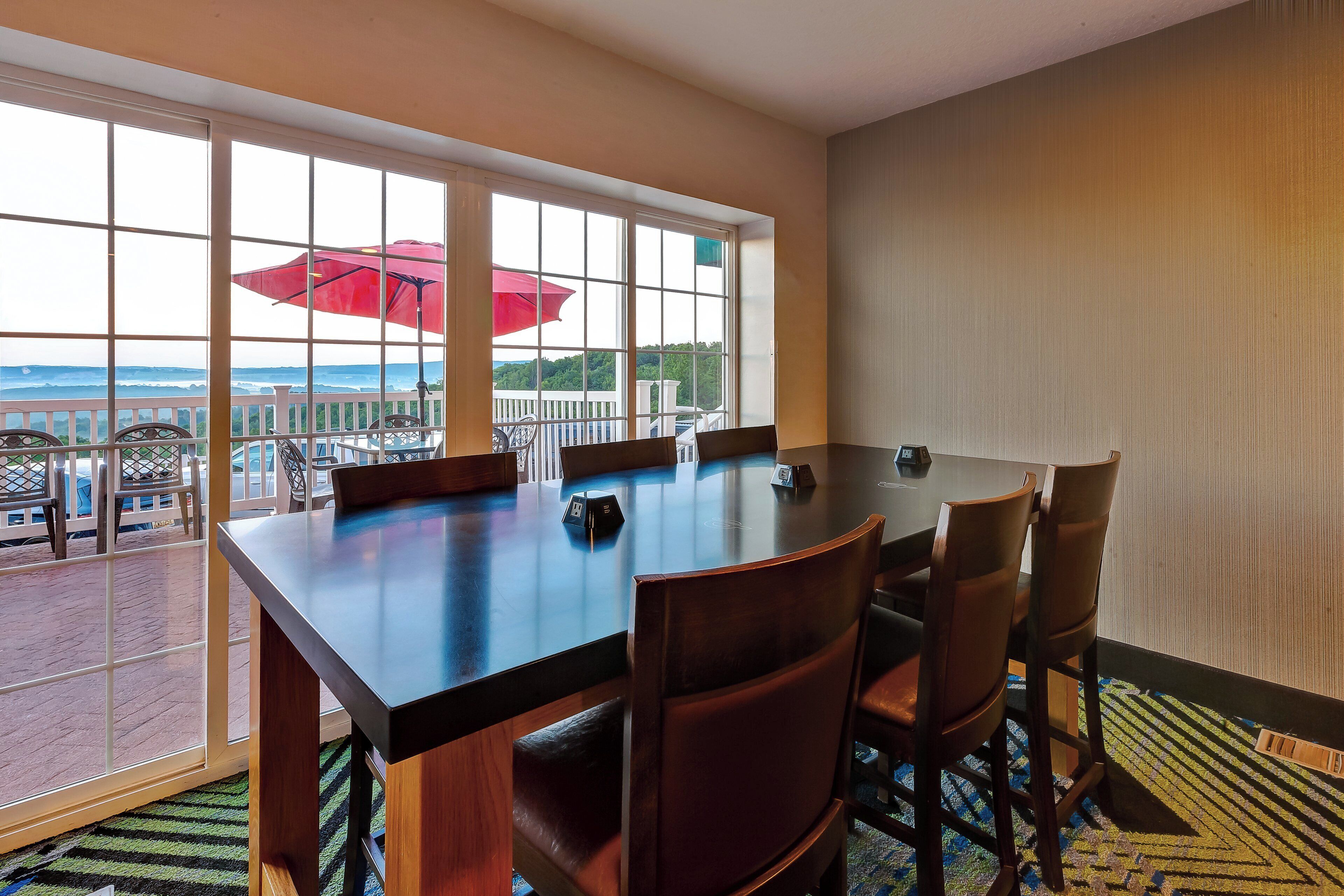 A conference room with a large table, chairs, and a view through large windows.