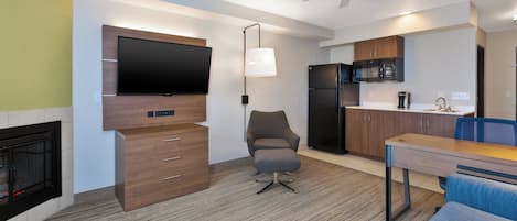 A modern kitchen with a flat-screen TV, a refrigerator, and a dining area with a table and chairs.