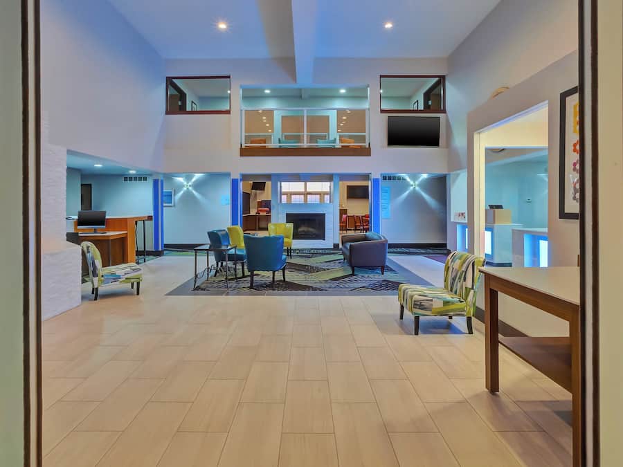 A spacious lobby with a high ceiling, a fireplace, and a seating area with chairs and a sofa.