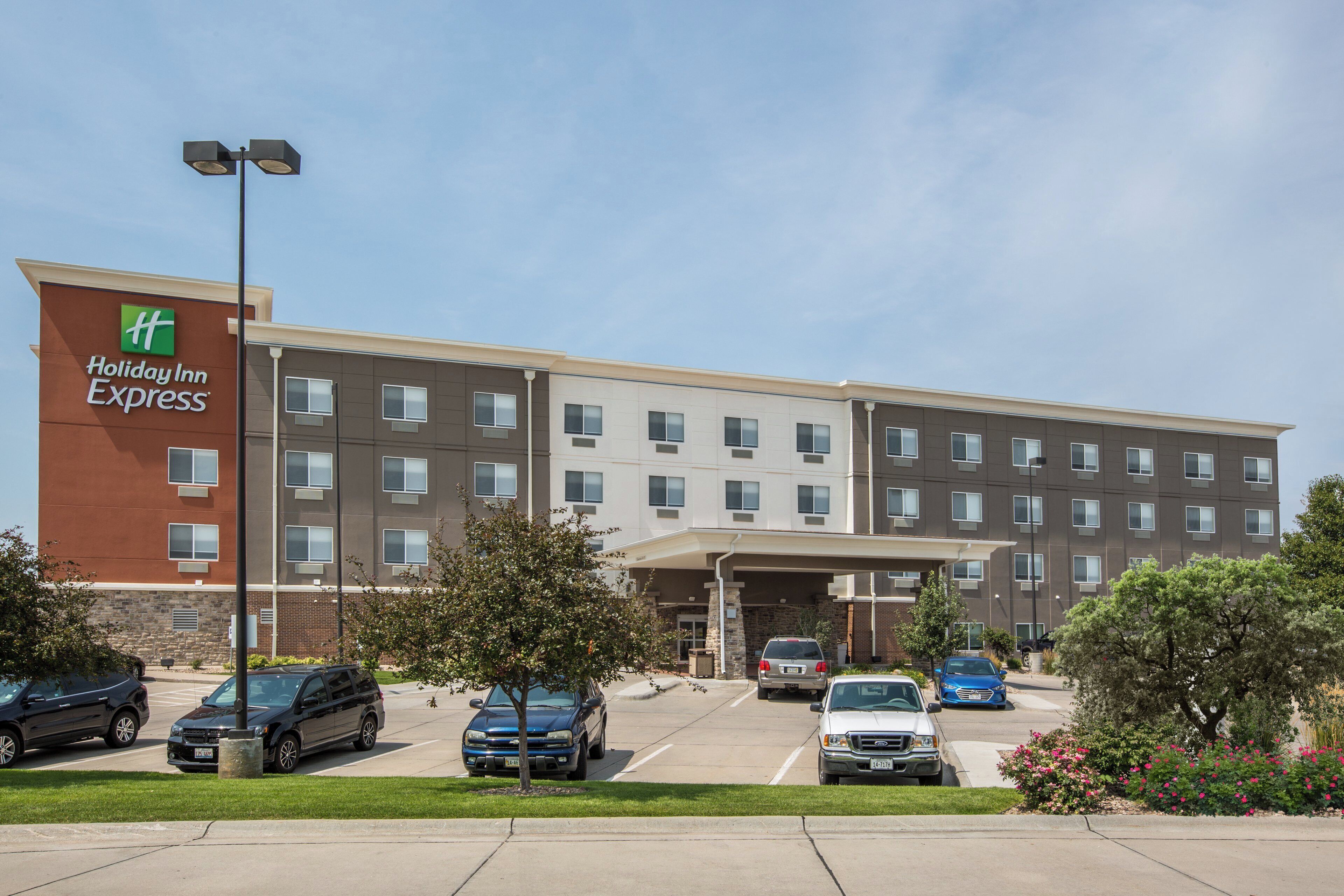 A Holiday Inn Express hotel with a parking lot, multiple cars, and a clear sky.