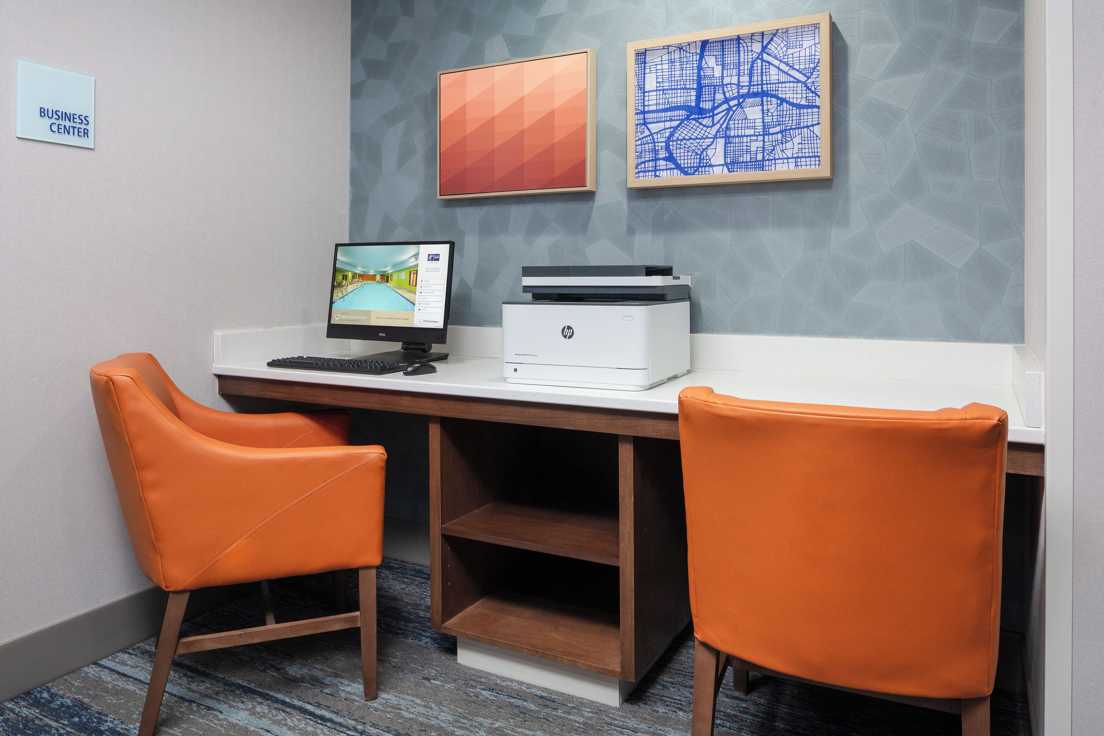 Un espacio de trabajo con dos sillas naranjas, un escritorio, una computadora e impresora.