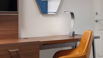 A modern room with a wooden desk, a single chair, a flat-screen TV, and a door.