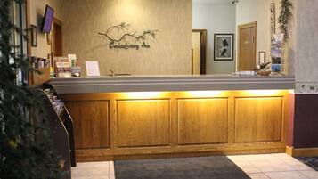 Un mostrador de recepción con diseño de paneles de madera, el letrero de Cedarberry Inn, una planta pequeña y una botella de vino en la barra.