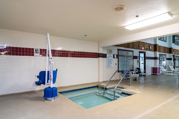 A swimming pool area with a lifeguard stand, a sign indicating pool rules, and lounge chairs.