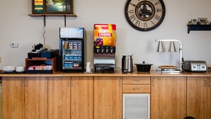 Een keukenblad met een koffieapparaat, een broodrooster, een waterkoker en een klok aan de muur.