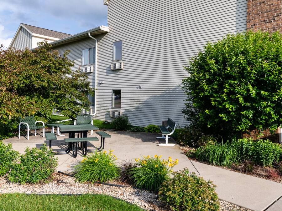 A residential building with a patio area featuring outdoor furniture and well-maintained landscaping.