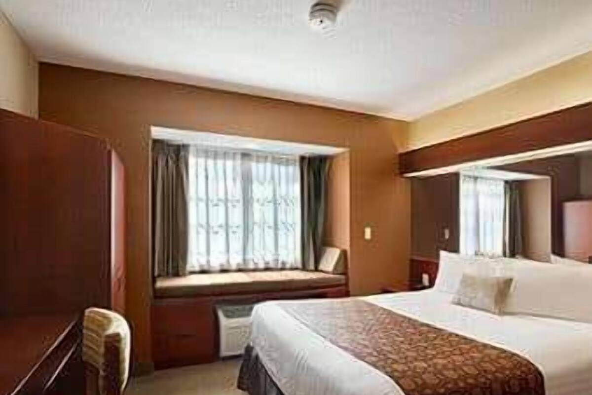 A hotel room with a large bed, a desk, and a window with curtains.