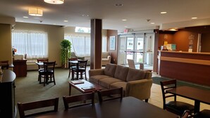 A hotel lobby with a reception desk, seating area, and a large window with curtains. - Microtel Inn & Suites by Wyndham Dover (Dover)