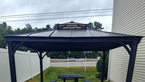 A covered picnic area with a table and benches, surrounded by a paved walkway and grass. - Microtel Inn & Suites by Wyndham Dover (Dover)
