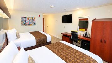 Ett hotellrum med två sängar, ett skrivbord, en stol, en tv och en garderob.