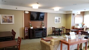 A hotel room with a flat-screen TV, a fireplace, a sofa, a dining table, and a coffee table. - Microtel Inn & Suites by Wyndham Dover (Dover)