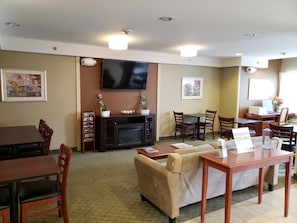 A hotel room with a flat-screen TV, a fireplace, a sofa, a dining table, and a coffee table. - Microtel Inn & Suites by Wyndham Dover (Dover)