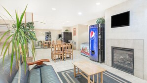 Ein modernes Wohnzimmer mit einer Couch, Sesseln, einem Couchtisch, einem Kamin und einem großen Wandfernseher.