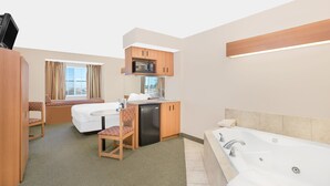 Ein kompaktes Hotelzimmer mit Bett, einer kleinen Küchenzeile, einer Sitzecke und einem Badezimmer mit Badewanne.