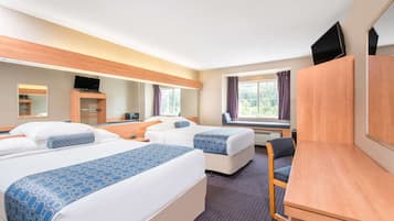 Habitación de hotel con dos camas, un escritorio, una silla, un televisor y una ventana con cortinas.