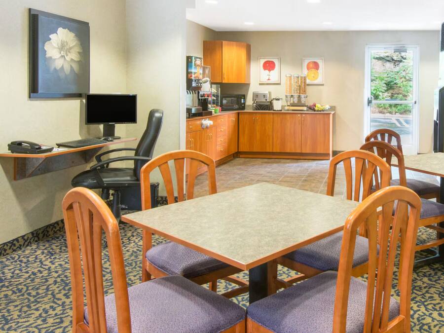 A hotel room with a dining area, a kitchen, a desk with a computer, and a large window.