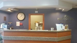 Un comptoir d’accueil avec une horloge, un miroir et une enseigne indiquant « MICROTEL BY WYNDHAM ».