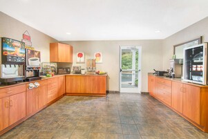 A modern kitchen with wooden cabinets, a coffee machine, and a view through the glass door.