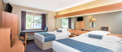 A hotel room with two beds, a desk, a chair, a TV, and a mirror.