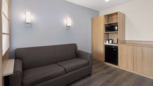 Una kitchenette moderna con microondas integrado, lavavajillas negro y armarios de madera.