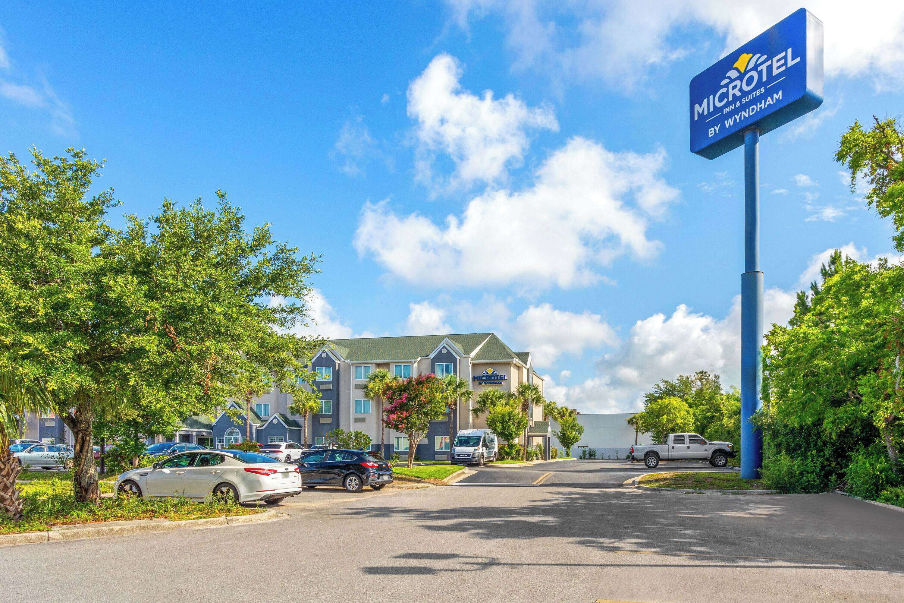A Microtel Inn & Suites by Wyndham with a parking lot, several cars, and a clear blue sky.