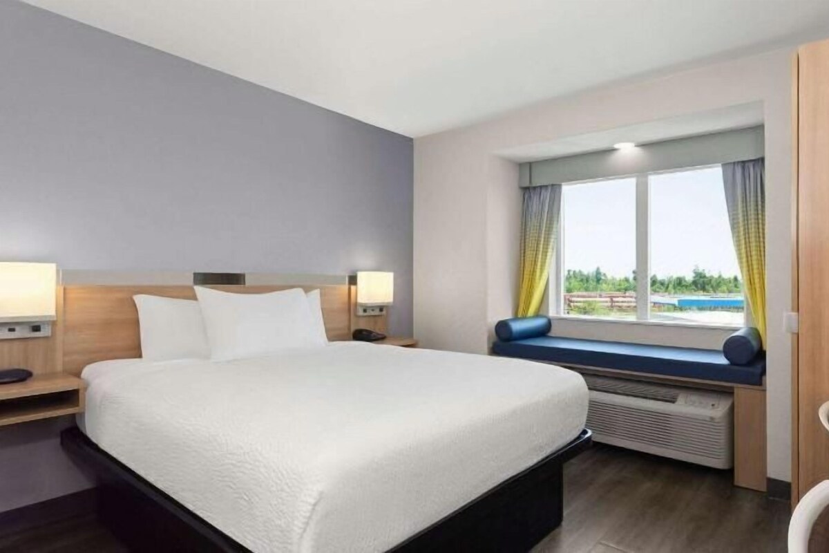 Una habitación de hotel con cama, mesitas de noche, una ventana con vistas y un escritorio.