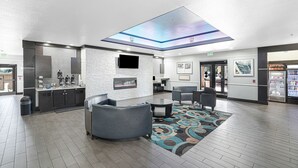 A modern lobby with a flat-screen TV, seating area, and a ceiling skylight. - Red Lion Inn & Suites HOU Airport Road (Houston)