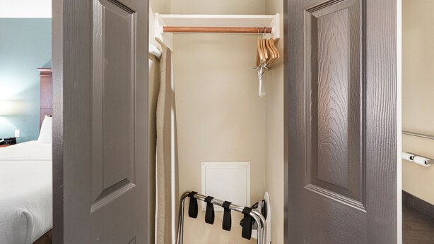 A narrow hallway with a coat rack, a door, and a shower area. - Red Lion Inn & Suites HOU Airport Road (Houston)