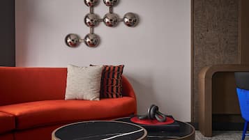 A modern living room with a red sofa, a wall-mounted spherical mirror art piece, a blue chair, and a round wooden coffee table.