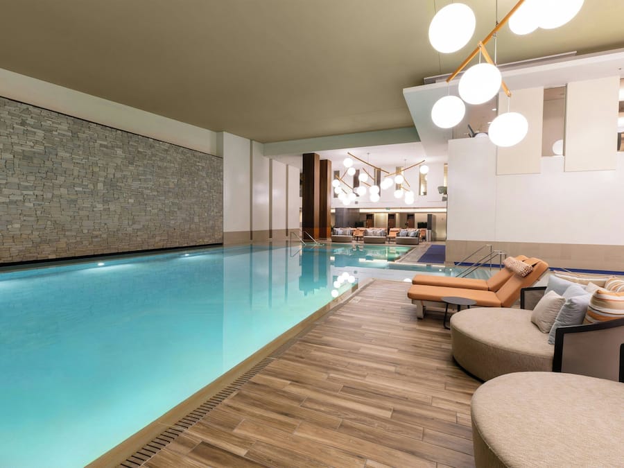 An indoor swimming pool with lounge chairs and a wooden deck.