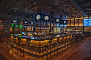 A bar area with multiple seating arrangements and a counter with a variety of bottles and glasses.