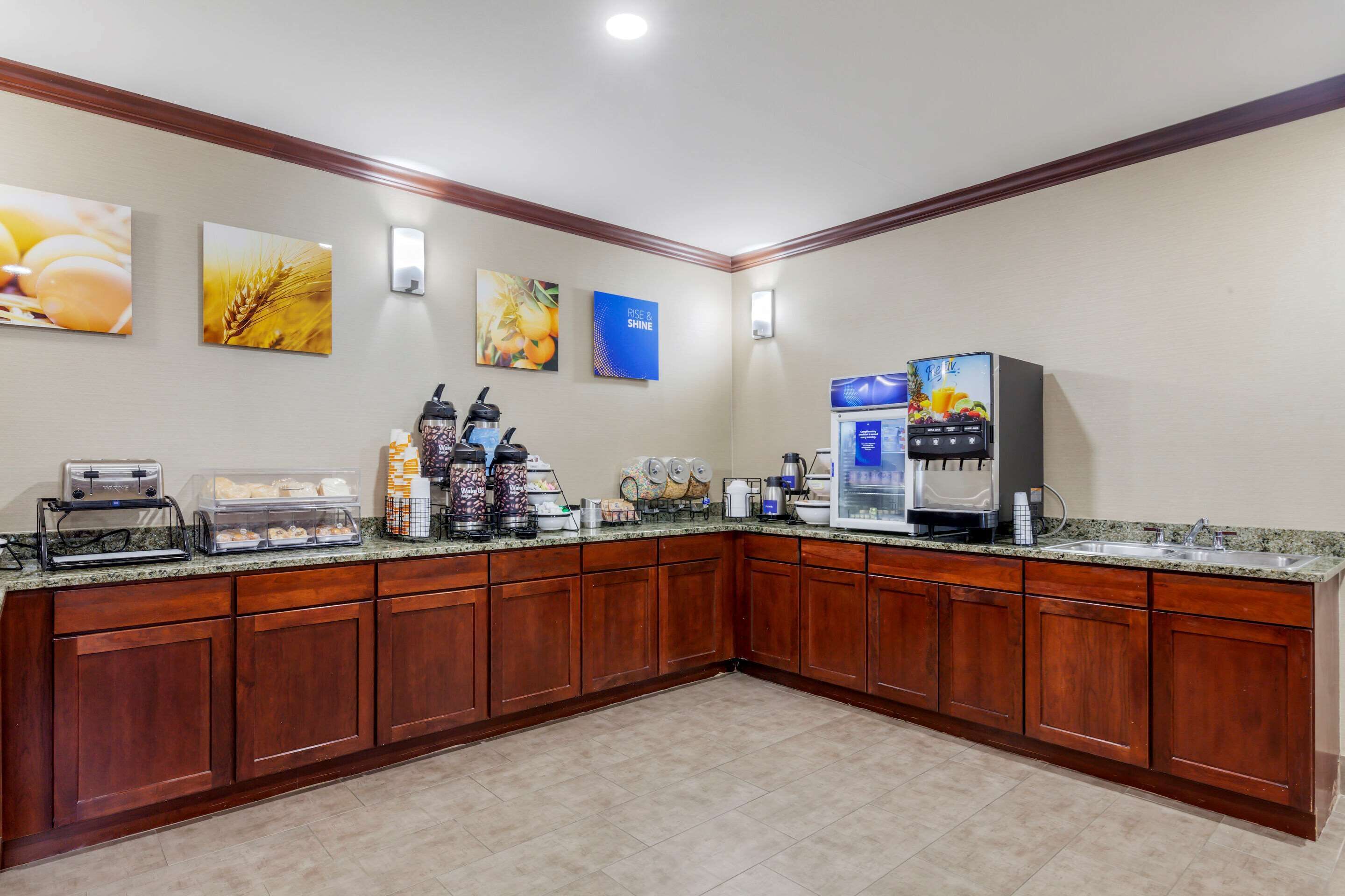 A kitchen with wooden cabinets, a granite countertop, and various appliances including a coffee maker and a refrigerator.