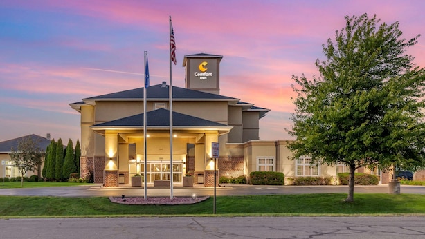 A Comfort Inn hotel with a brick facade, a flagpole with an American flag, and a well-lit entrance. - Comfort Inn Plover-Stevens Point (Plover)