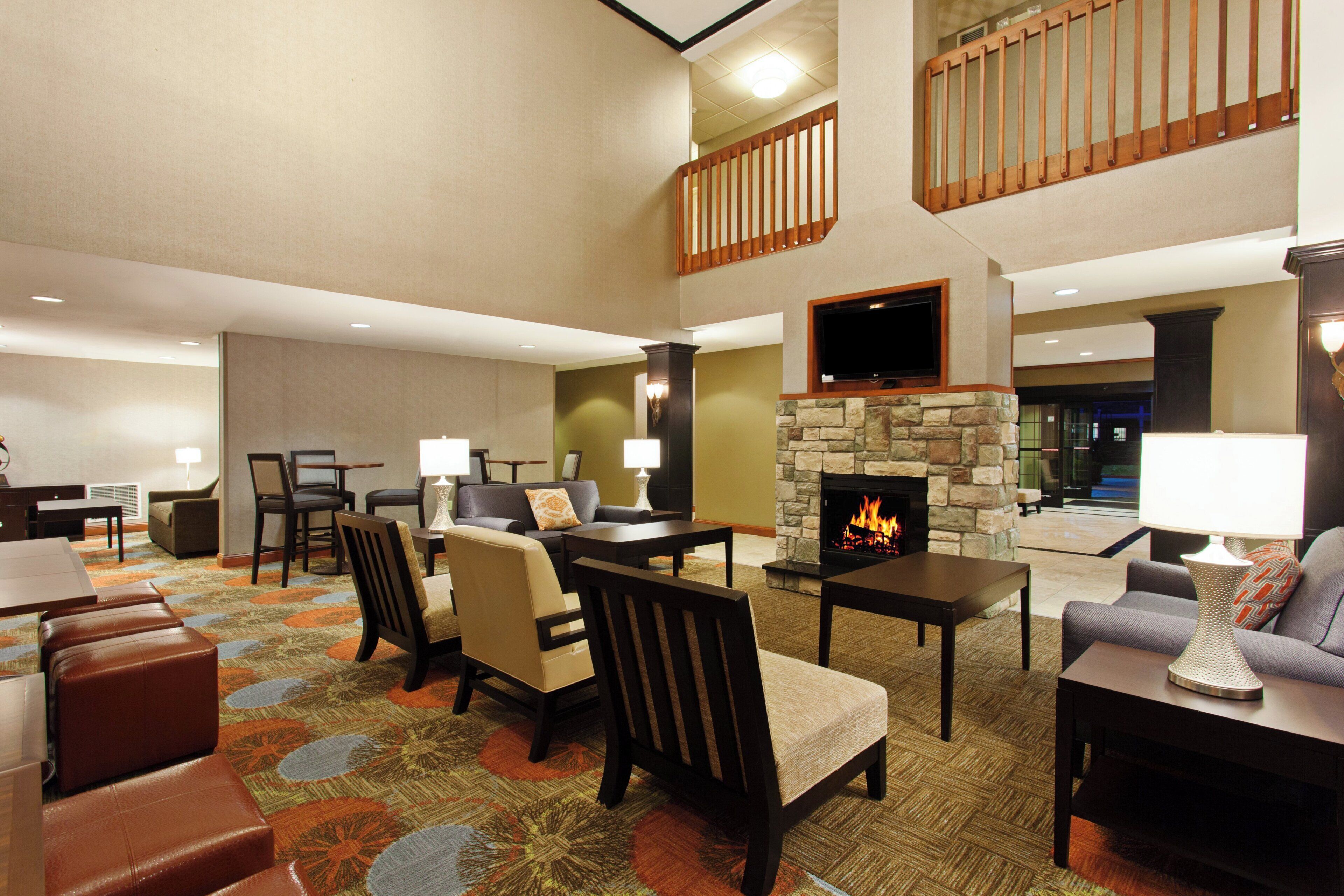 A hotel lobby with a fireplace, seating area, and a television mounted on the wall.