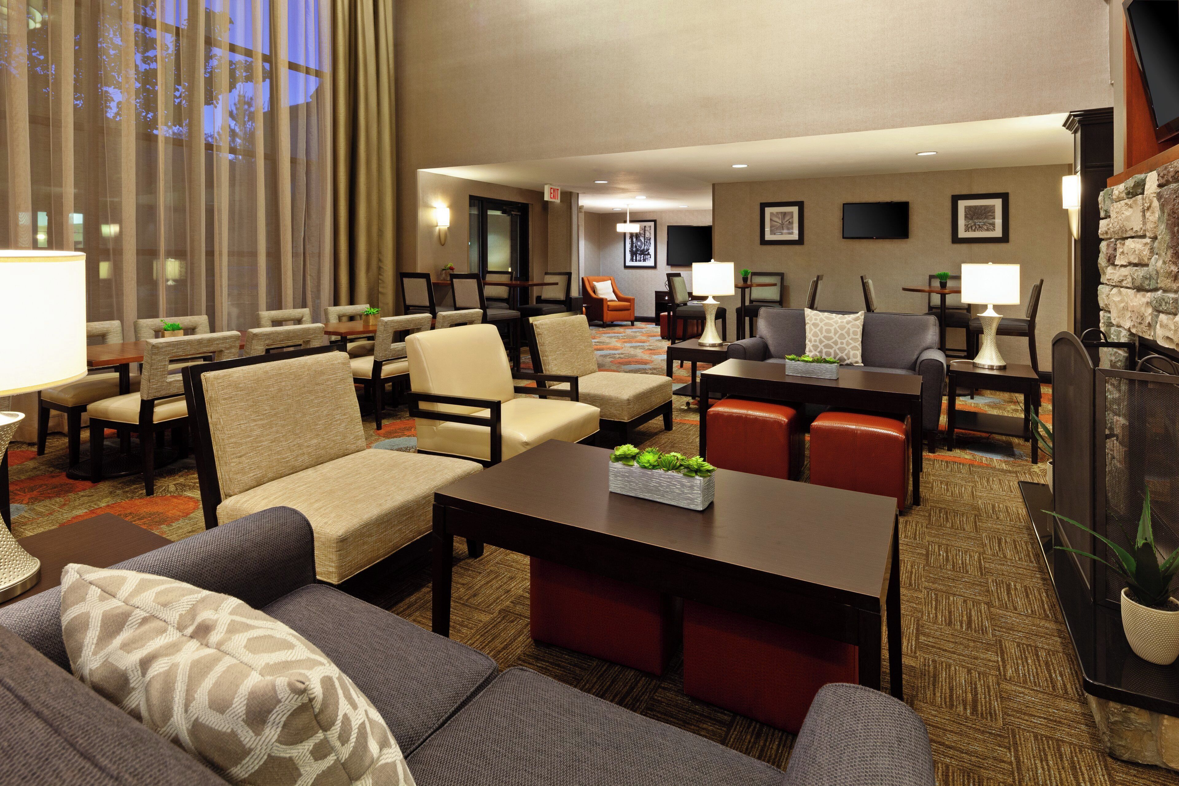 A hotel lobby with seating areas, a fireplace, and a television.