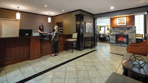 A modern kitchen with a bar area, a stone fireplace, and a seating area with a sofa and armchairs. - Staybridge Suites Fairfield Napa Valley Area by IHG (Fairfield)