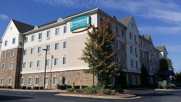 A Staybridge Suites hotel with a stone facade, multiple windows, and a clear sky.
